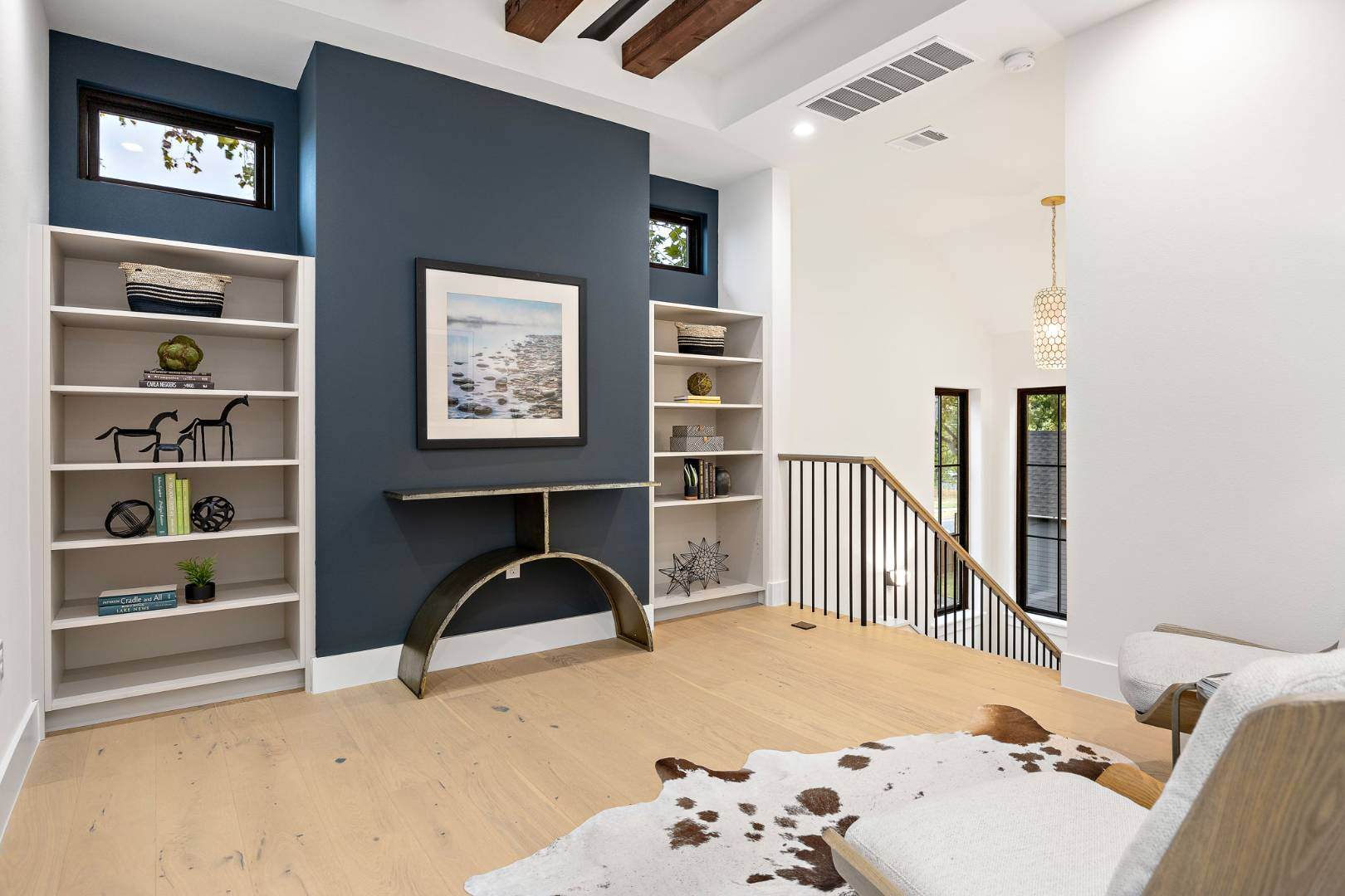 Stylish reading or workspace area: Includes built-in shelving against a dark accent wall, a framed photo, and a unique half-circle console table. | CKN Homes