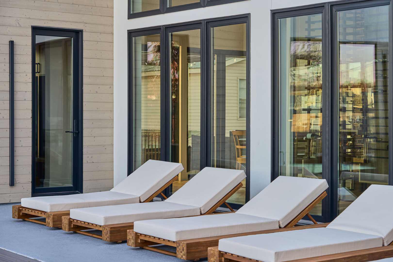 Luxury outdoor lounge chairs by a modern home’s glass windows. Austin, TX | CKN Homes