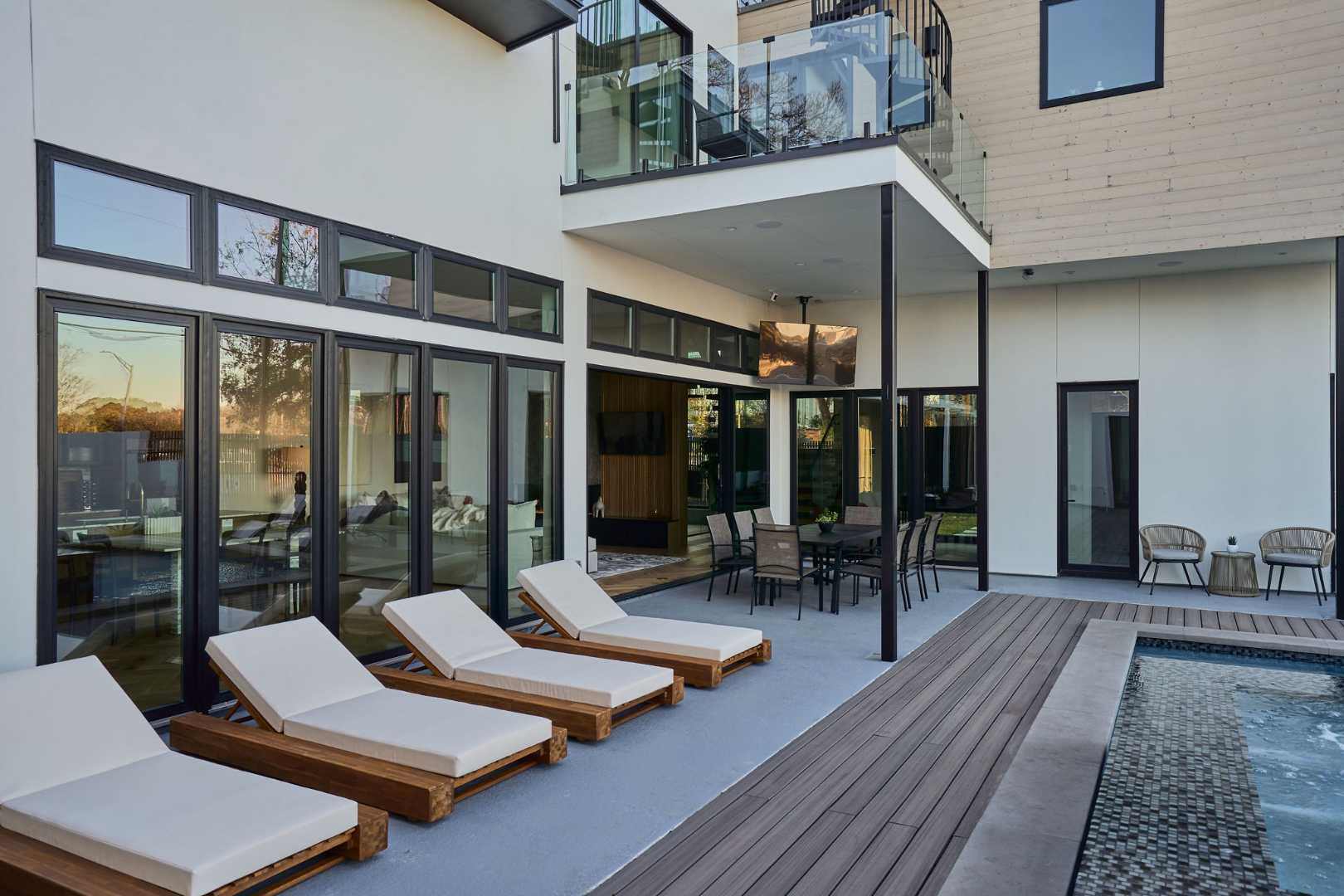 Stylish poolside patio with wooden lounge chairs and dining. Austin, TX | CKN Homes