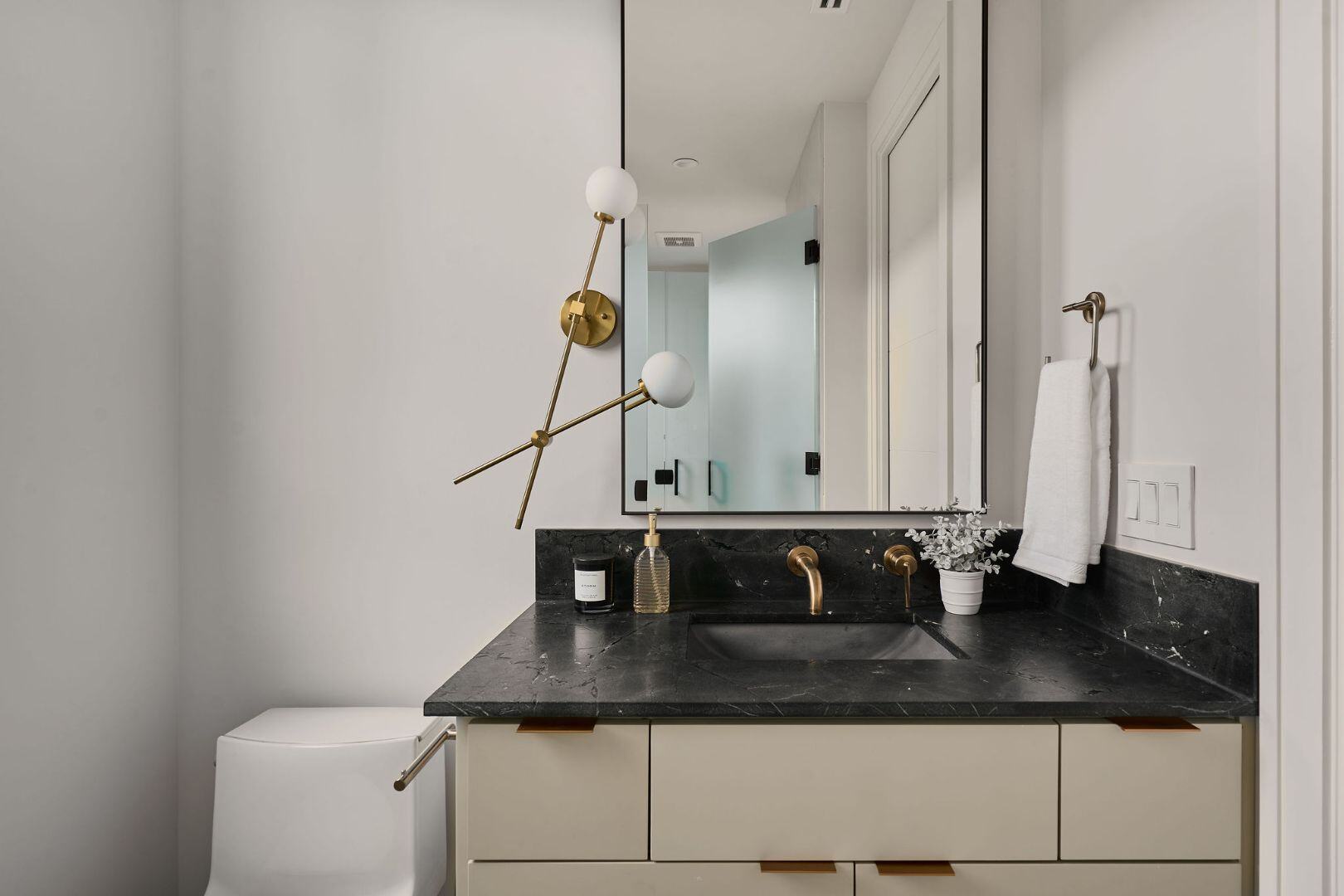 Modern bathroom with gold accents and black vanity. Austin, TX | CKN Homes