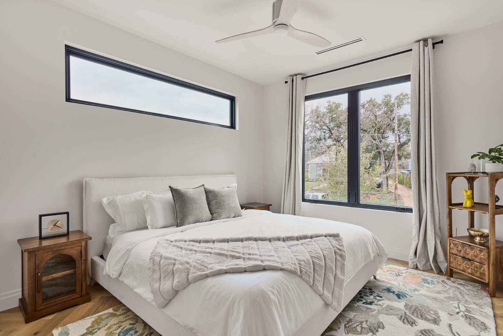 Bright bedroom with white bed and large windows. Austin, TX | CKN Homes