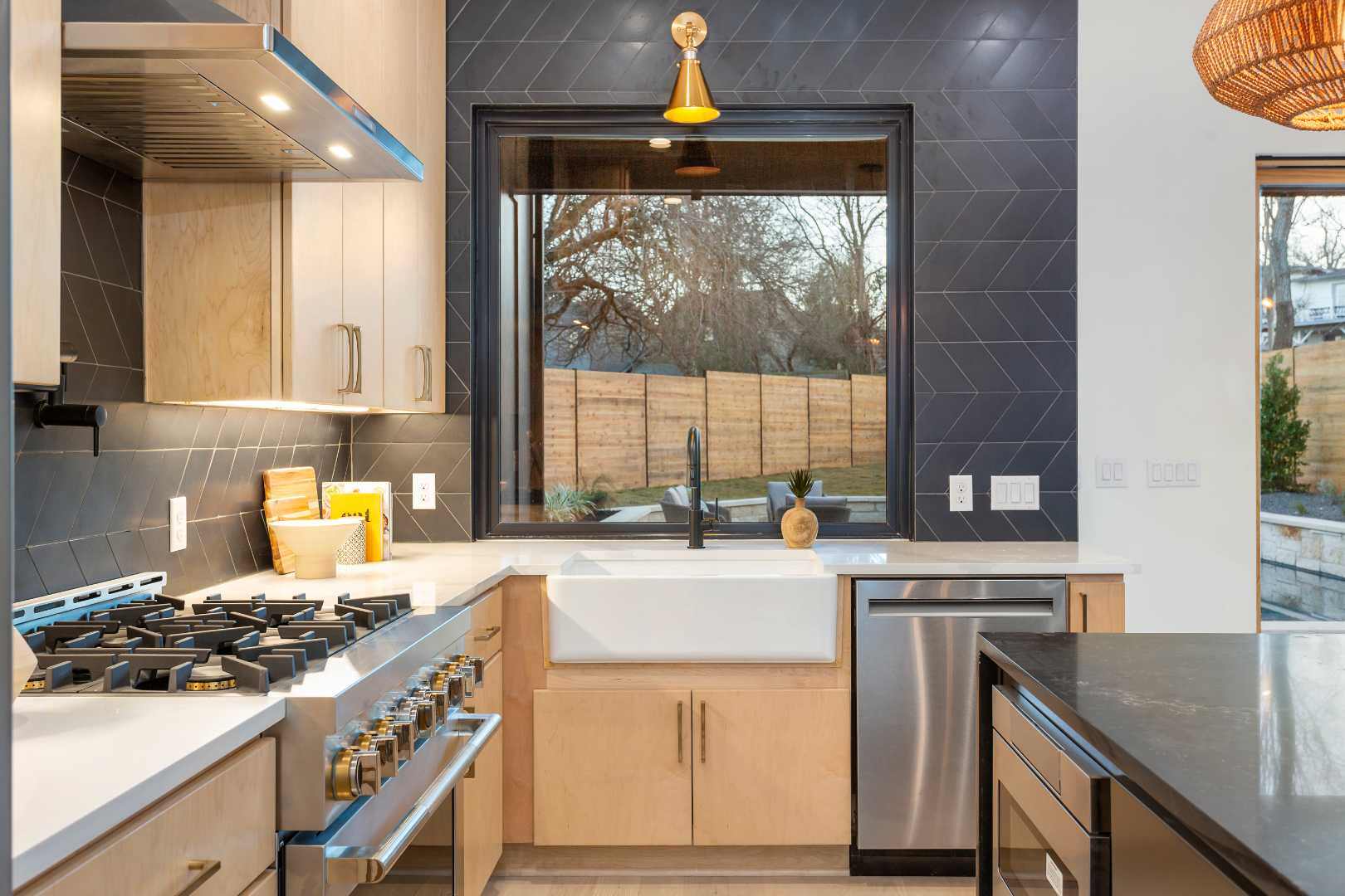 Kitchen detail with black accents: Includes a modern farmhouse sink, stainless steel appliances, and a large window providing ample natural light. | CKN Homes