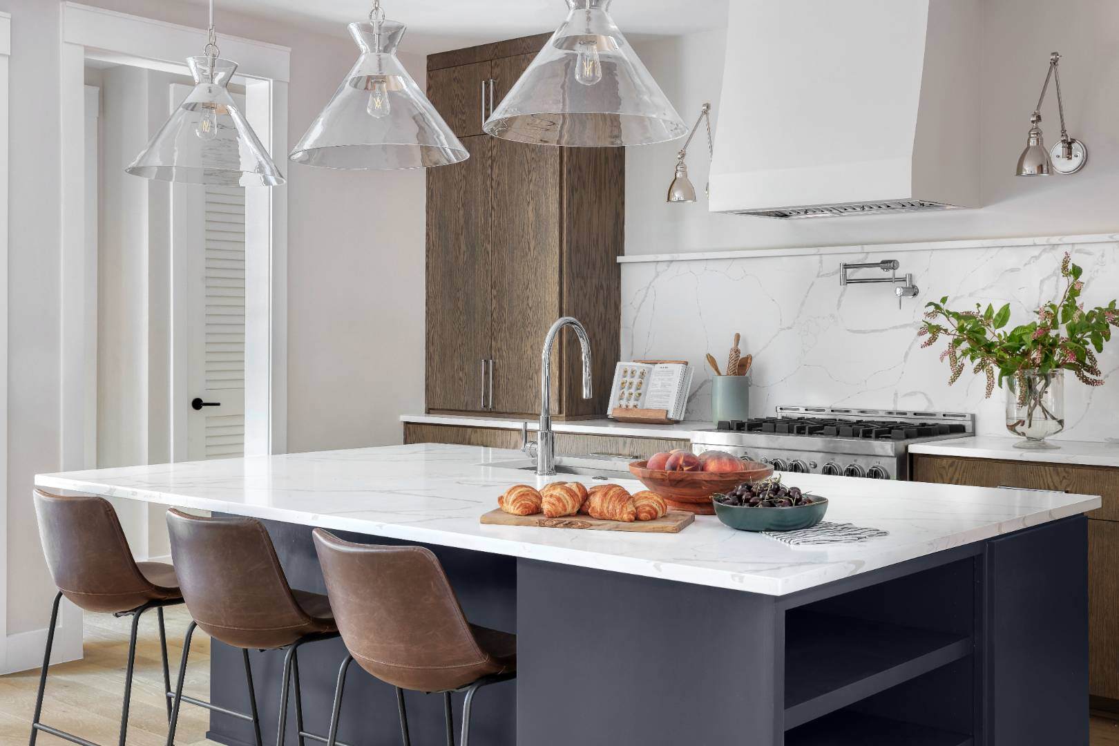 Bright and stylish kitchen: Highlights a marble-topped island with seating, stainless steel appliances, and pendant lighting above the workspace. | CKN Homes